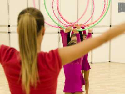 Su indicazione dell'istruttrice, le bambine alzano i cerchi stringendoli ben saldi sopra le loro teste
